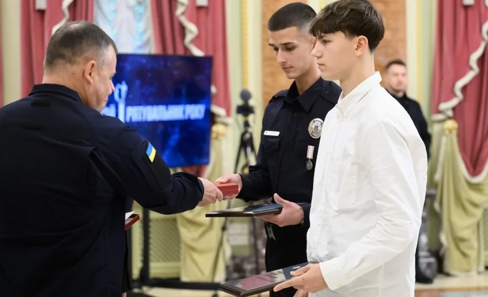 Чоловіки в форміст вручають нагороди молодим людям у залі