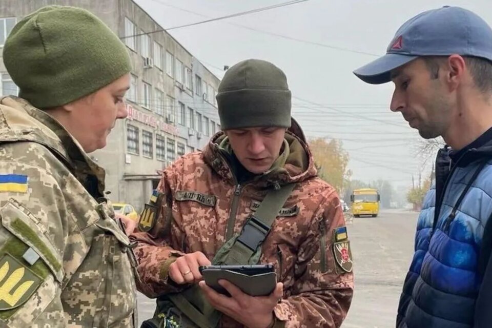 Двоє військових ЗСУ з планшетом розмовляють із цивільним на вулиці